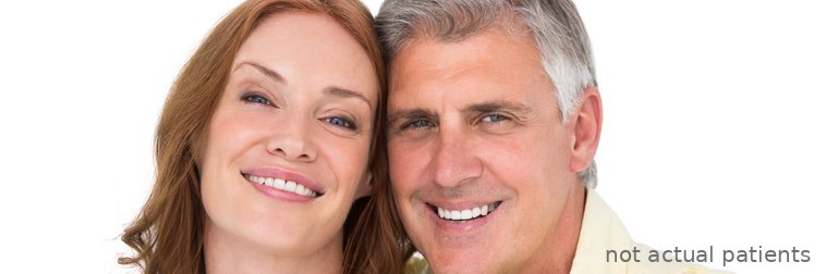 Smiling middle-aged couple posing cheek to cheek, showing bright, natural-looking smiles (models, not actual patients)